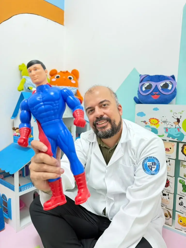 Psicólogo Denis Neves brincando com boneco na sala infantil da Clínica Psi